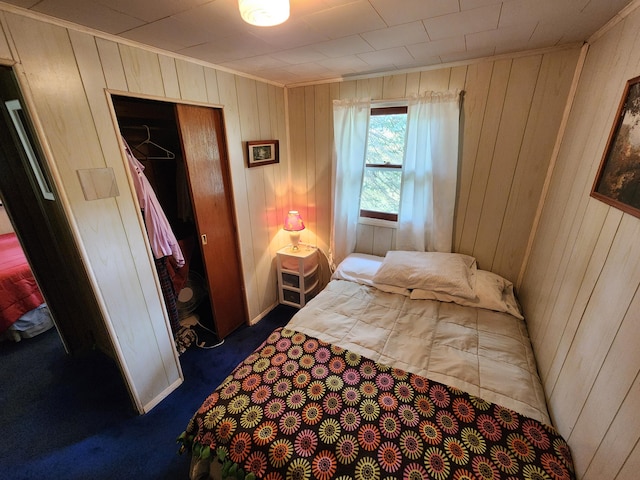 carpeted bedroom featuring wood walls and a closet