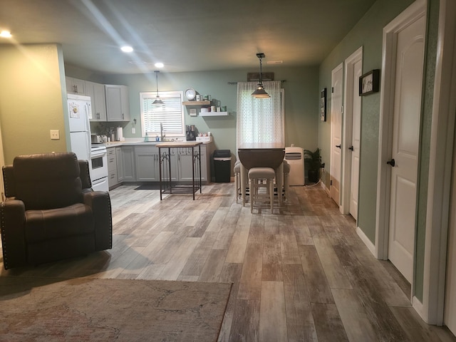 kitchen featuring white cabinetry, white refrigerator, sink, stove, and light hardwood / wood-style floors