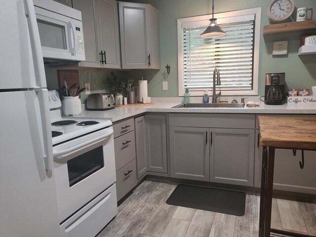 kitchen featuring gray cabinets, hanging light fixtures, white appliances, and sink