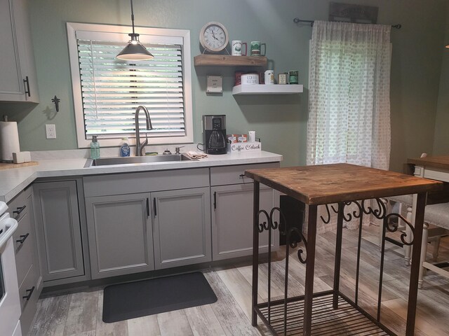 kitchen with sink, light hardwood / wood-style flooring, hanging light fixtures, and gray cabinetry