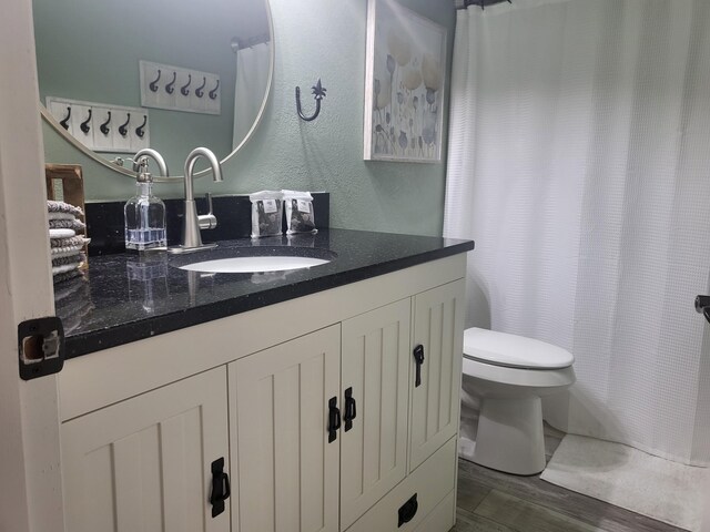 bathroom featuring wood-type flooring, toilet, and vanity