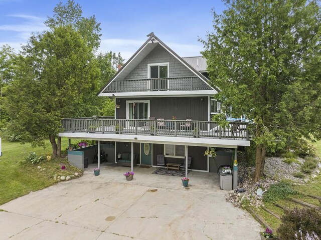 rear view of house with driveway, a deck, and a carport