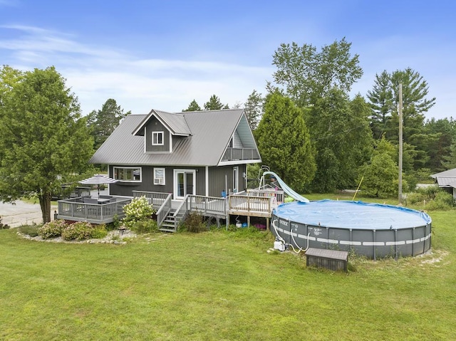 back of property featuring an outdoor pool, a deck, metal roof, and a yard