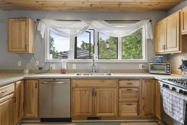 kitchen featuring light countertops, appliances with stainless steel finishes, a sink, and a toaster