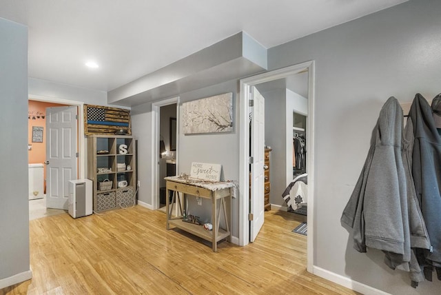 hall with light wood-style floors and baseboards