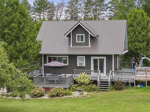 back of property featuring a wooden deck, metal roof, and a yard