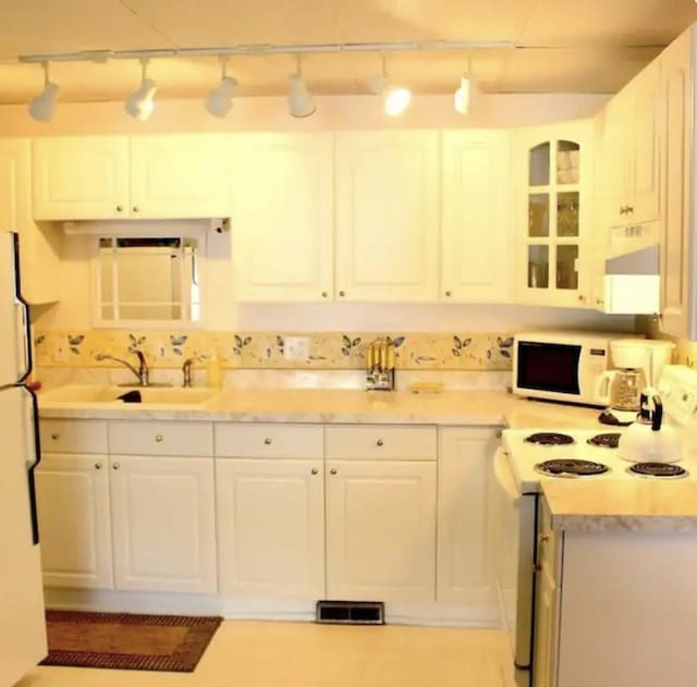 kitchen with range hood, white cabinetry, track lighting, and white appliances