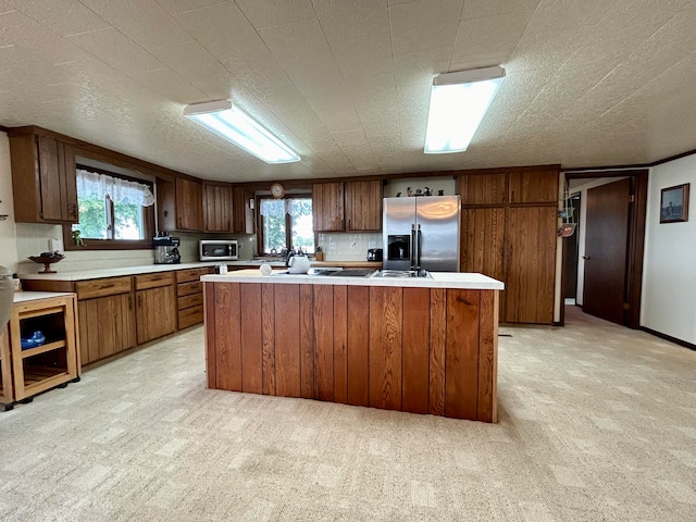 kitchen featuring a kitchen island, stainless steel appliances, a healthy amount of sunlight, and light colored carpet