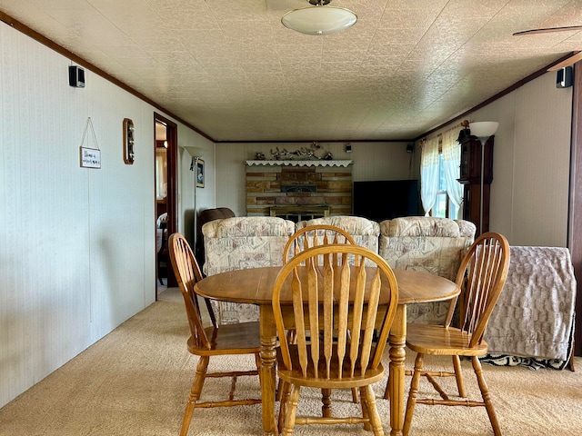 carpeted dining room featuring ornamental molding, a textured ceiling, and a stone fireplace