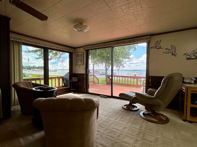 living room with plenty of natural light, a water view, ceiling fan, and carpet flooring