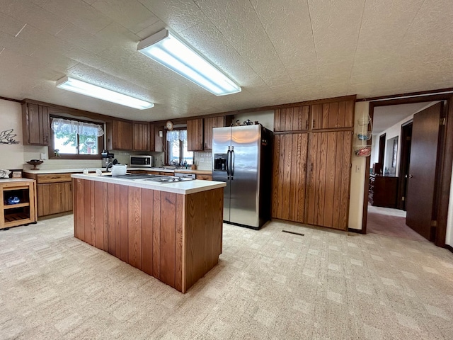 kitchen with sink, a center island, appliances with stainless steel finishes, and light carpet