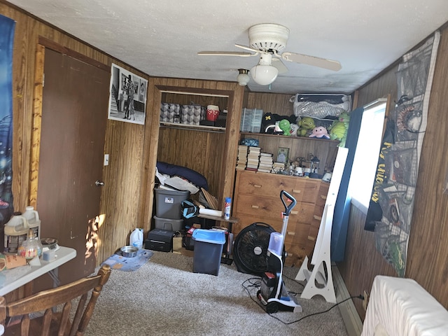 interior space with carpet flooring, ceiling fan, and wooden walls