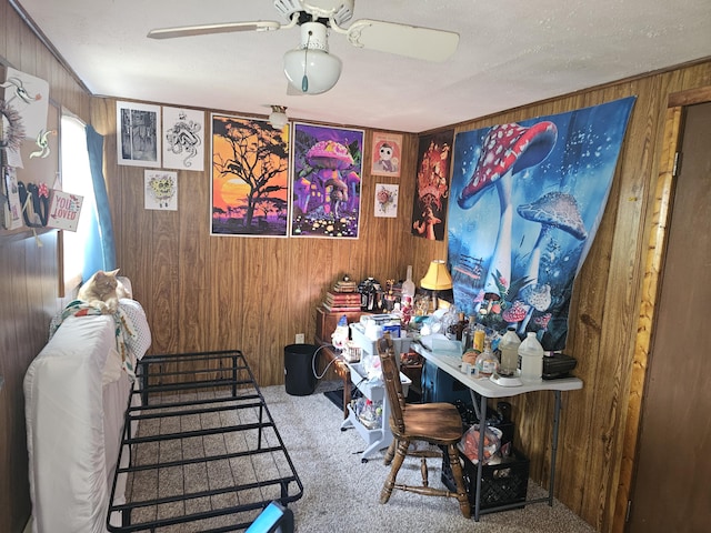 office area with carpet flooring, ceiling fan, and wooden walls