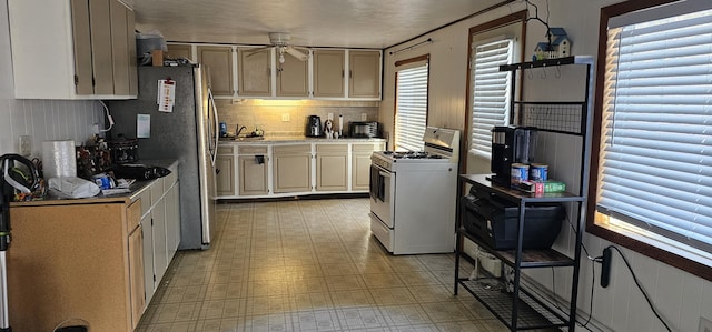 kitchen with a textured ceiling, plenty of natural light, gas range gas stove, and ceiling fan