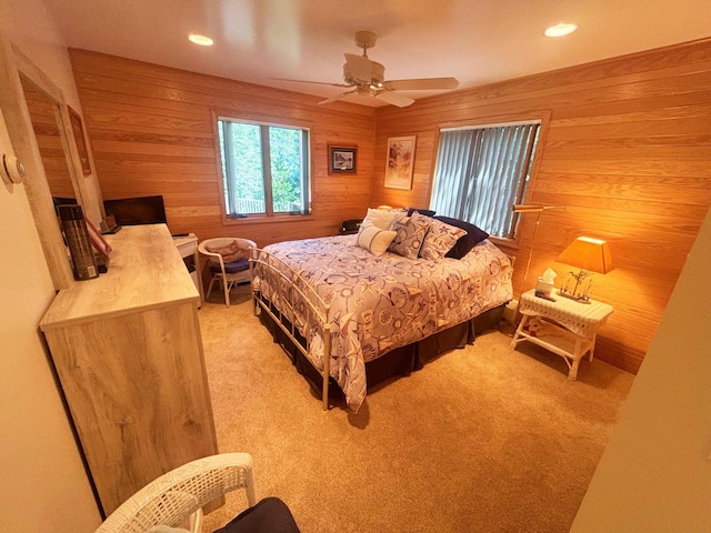 bedroom with a ceiling fan, recessed lighting, light carpet, and wood walls