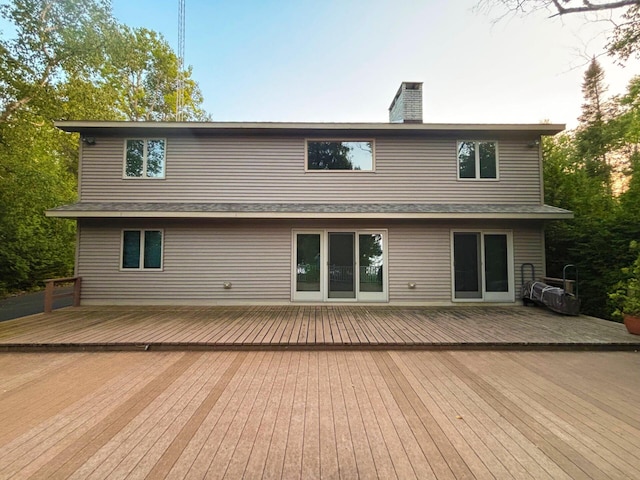 back of property featuring a chimney and a deck