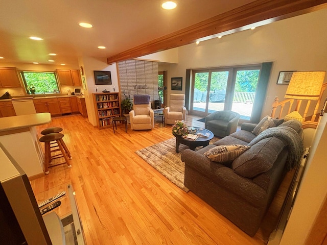 living room with recessed lighting, plenty of natural light, light wood-style flooring, and beamed ceiling