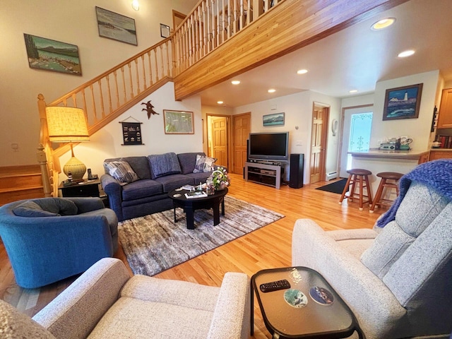 living area featuring stairs, a towering ceiling, light wood-style flooring, and recessed lighting