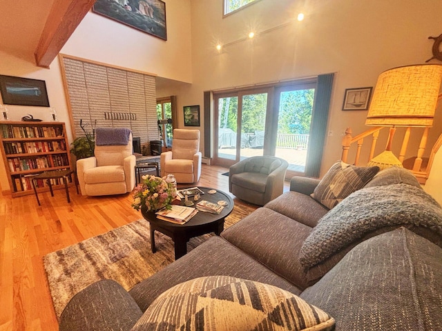 living area with a towering ceiling, a fireplace, and wood finished floors