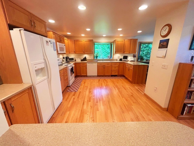 kitchen featuring white appliances, light wood finished floors, a sink, and recessed lighting