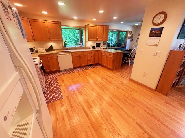 kitchen with light wood-style flooring, a peninsula, white dishwasher, range with electric stovetop, and recessed lighting