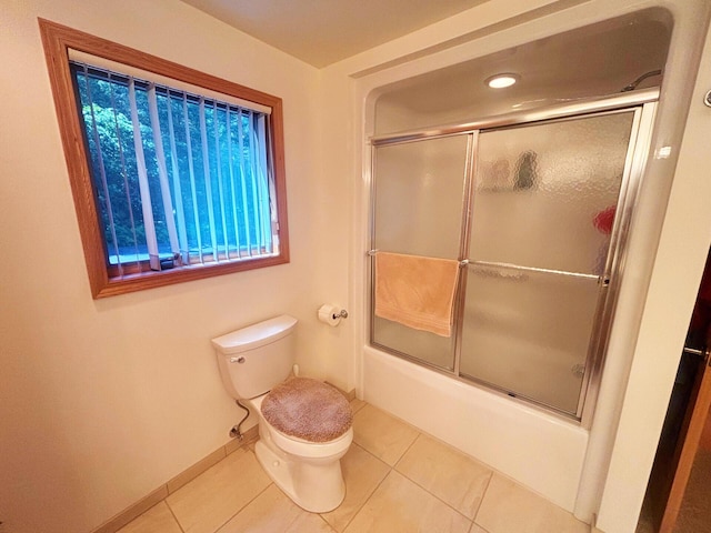 full bath with baseboards, shower / bath combination with glass door, toilet, and tile patterned floors