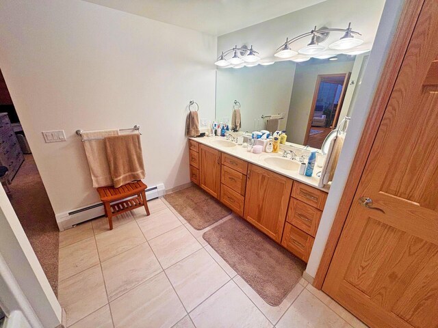 bathroom featuring tile patterned flooring, a sink, baseboard heating, and double vanity