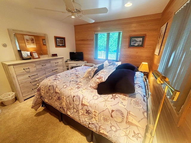 carpeted bedroom with ceiling fan and wood walls