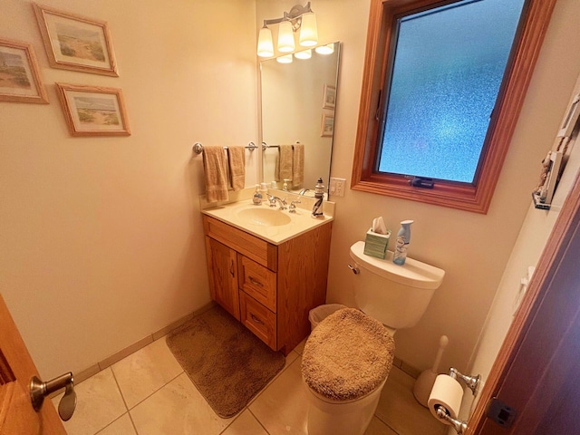 half bath with toilet, tile patterned flooring, vanity, and baseboards