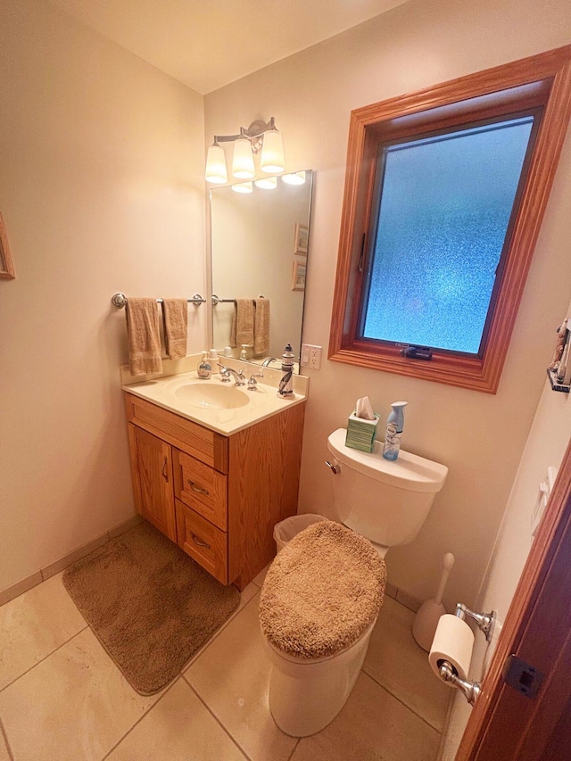 half bathroom with toilet, tile patterned floors, baseboards, and vanity