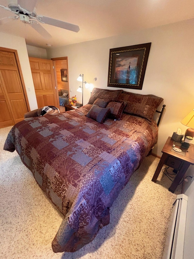 carpeted bedroom with baseboard heating and a ceiling fan