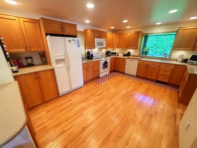 kitchen with light wood-style flooring, recessed lighting, white appliances, light countertops, and brown cabinets