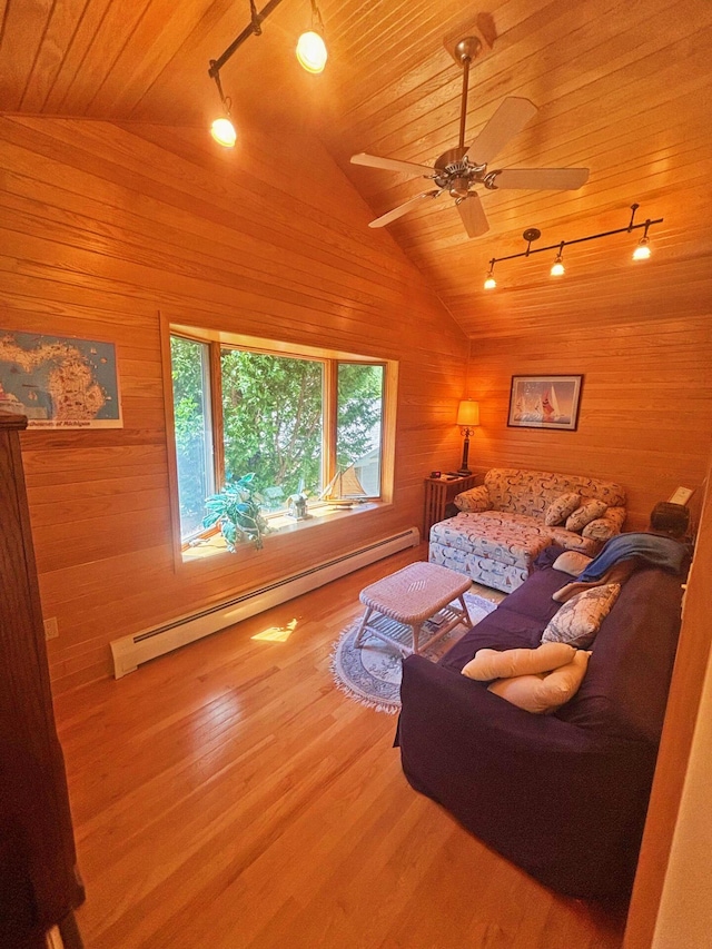 living room with vaulted ceiling, a baseboard radiator, wood finished floors, and wooden walls