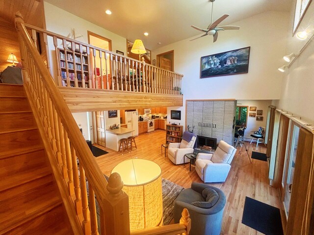 living room featuring recessed lighting, a high ceiling, a ceiling fan, wood finished floors, and stairs