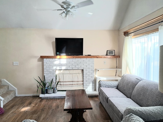 living room featuring lofted ceiling, ceiling fan, dark wood-type flooring, and a brick fireplace