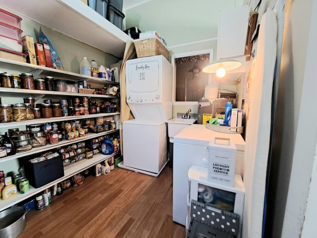 laundry room featuring stacked washer / dryer and dark wood-type flooring