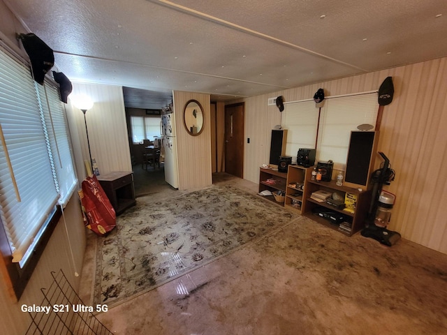 living room featuring wood walls, concrete flooring, and a textured ceiling