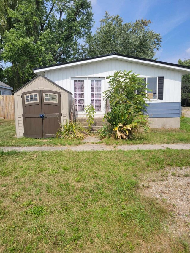 view of front of property with a front lawn and a storage shed