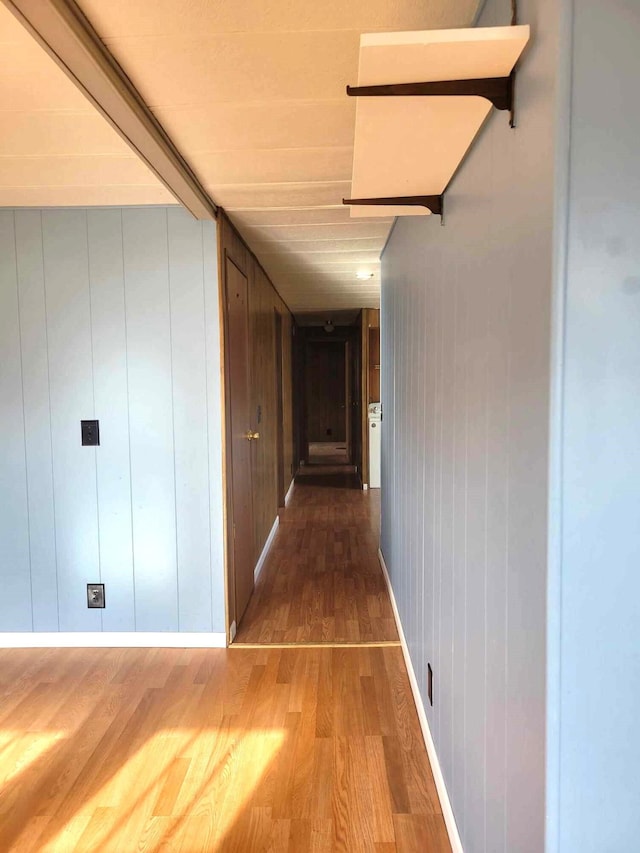 corridor with hardwood / wood-style flooring and wooden walls