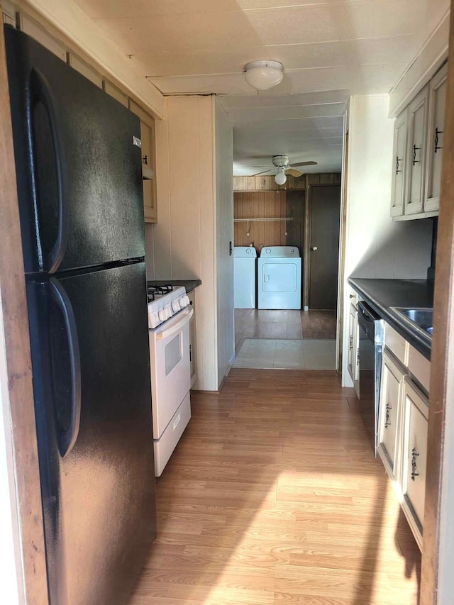 kitchen with light wood-type flooring, ceiling fan, black appliances, and washing machine and clothes dryer