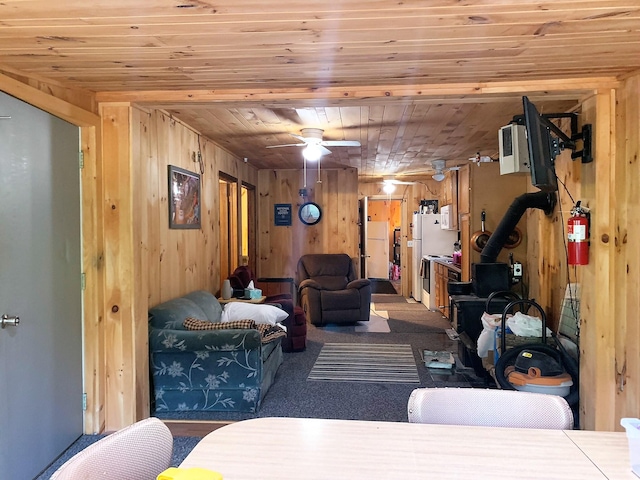 carpeted living room featuring ceiling fan, wooden walls, and wood ceiling