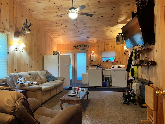 carpeted living room featuring wood ceiling, ceiling fan, washing machine and clothes dryer, vaulted ceiling, and wood walls