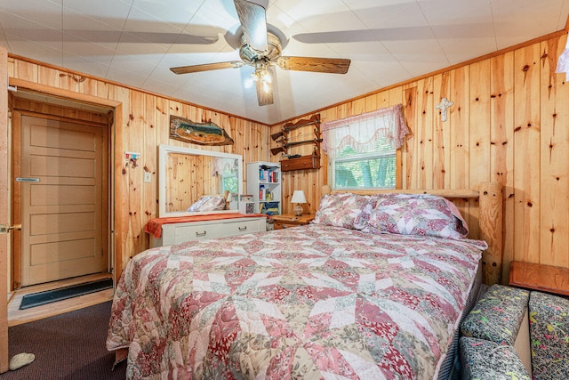 carpeted bedroom featuring wooden walls and ceiling fan