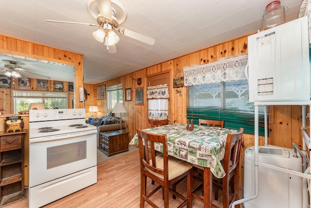 kitchen featuring electric range, ceiling fan, wood walls, and light wood-type flooring