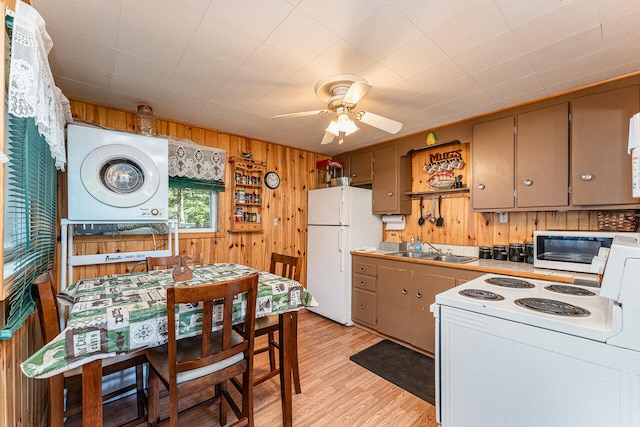 kitchen featuring light hardwood / wood-style flooring, ceiling fan, wood walls, white appliances, and sink