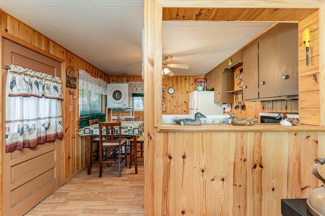 kitchen featuring ceiling fan, white refrigerator, kitchen peninsula, wooden walls, and light wood-type flooring