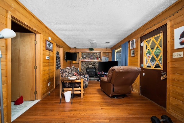 living room featuring wood walls, a textured ceiling, and hardwood / wood-style floors