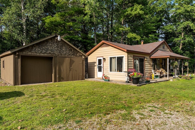 view of front of home featuring a garage, a front yard, and an outbuilding