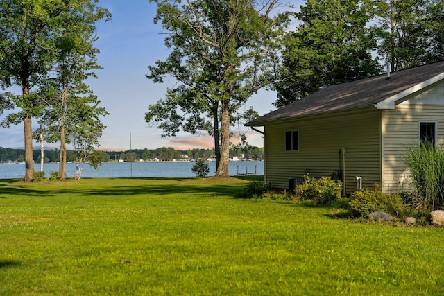 yard at dusk with cooling unit and a water view