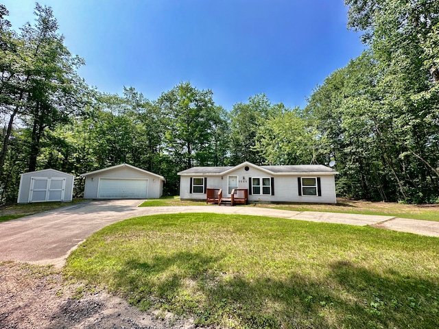 view of front of property featuring a front yard, a garage, and an outbuilding